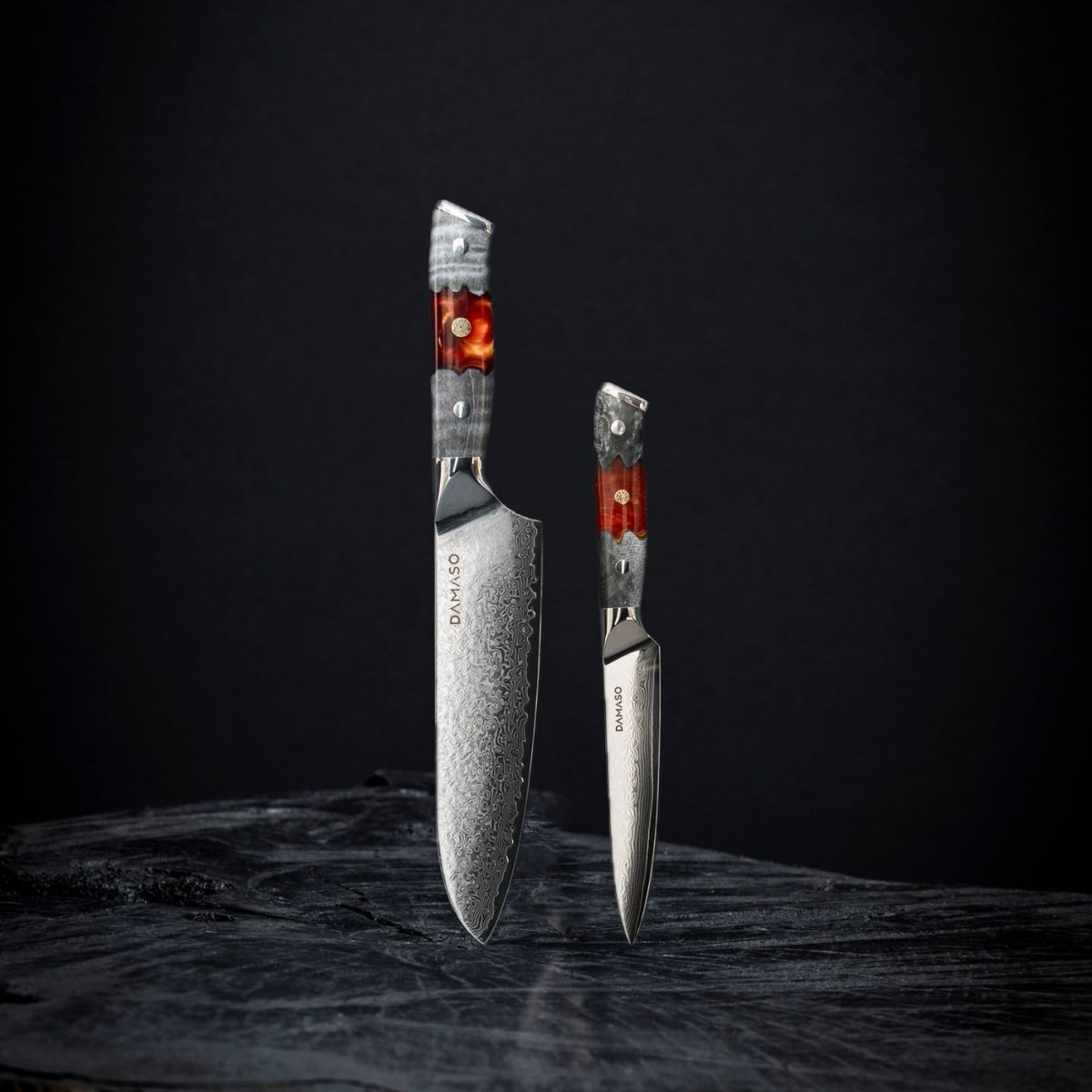 Messerset Red Ash DAMASO – Japanisches Santoku 17,8 cm und Allzweckmesser 12,5 cm aus Damaststahl mit VG10 Stahlkern vor dunklem Hintergrund